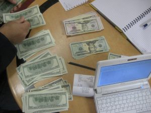 Personne en train de compter des dollars sur un bureau