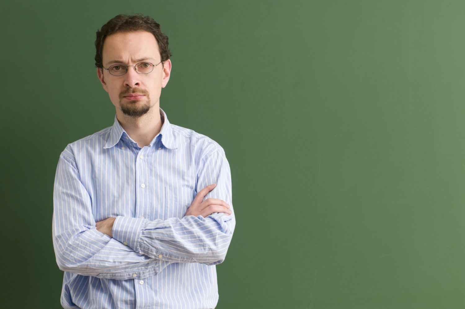 serious teacher with arms crossed at blackboard