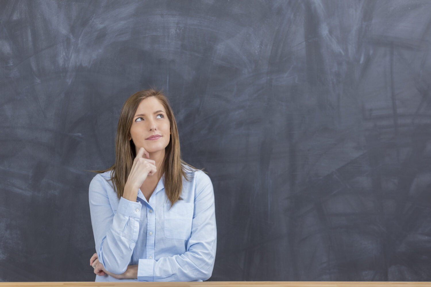 Corrections de copies : "payé 16,22 euros, que vais-je faire de cette richesse ?" Thinking woman ponders ideas in front of blank chalkboard