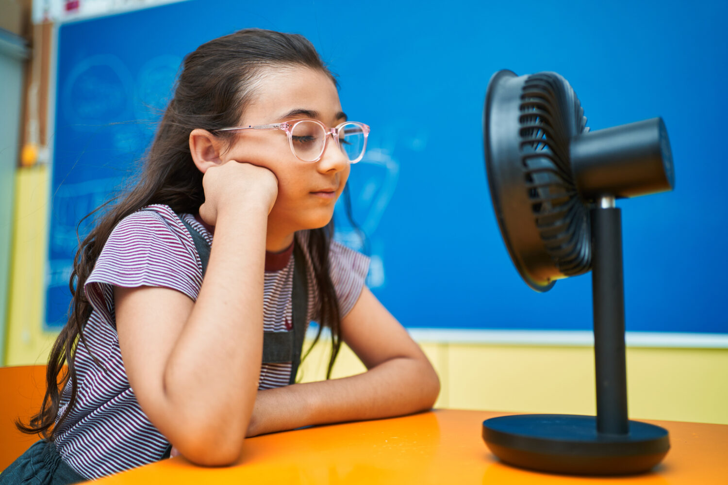 Canicule : 2213 établissements scolaires fermés hier, 136 aujourd’hui School girl interacting with electric fan at classroom