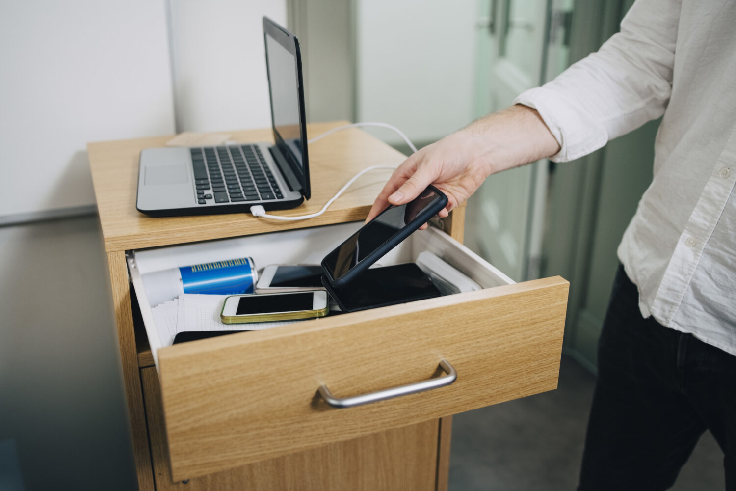 Midsection of student keeping smart phone in drawer during exam