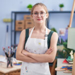 Young caucasian woman artist smiling confident standing with arms crossed gesture at art studio